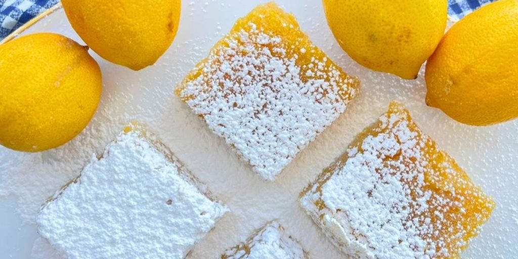 4 slices of high altitude lemon bars with shortbread crust surrounded by fresh lemons