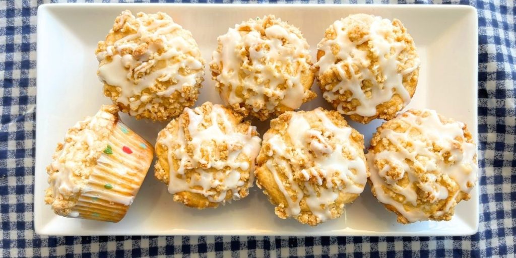 7 high altitude peach cobbler muffins with streusel and drizzled icing