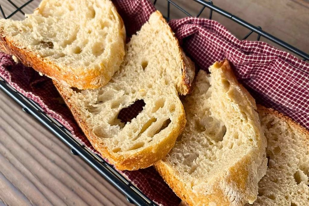 4 slices of sourdough bread in a black wire basket with a red tea towel