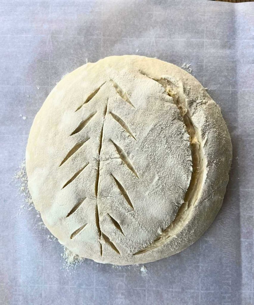 a loaf of sourdough bread dough lightly floured and scored