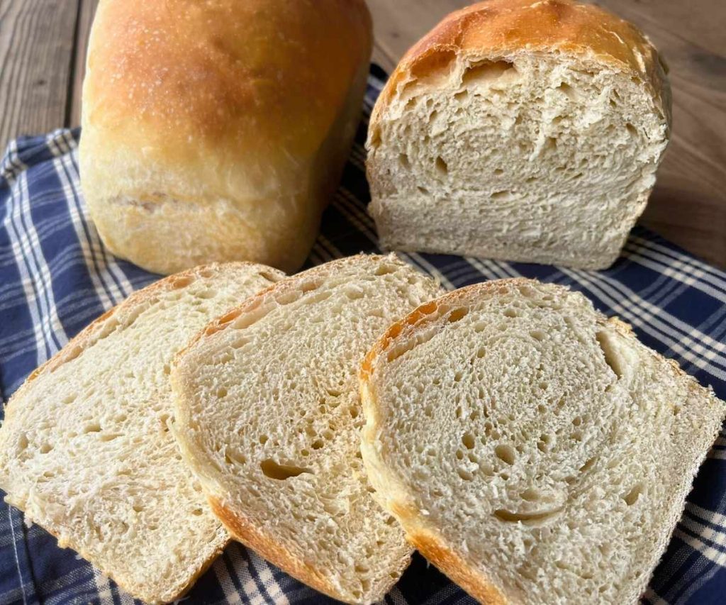 2 loaves of high altitude sourdough sandwich bread with 3 slices cut off one loaf