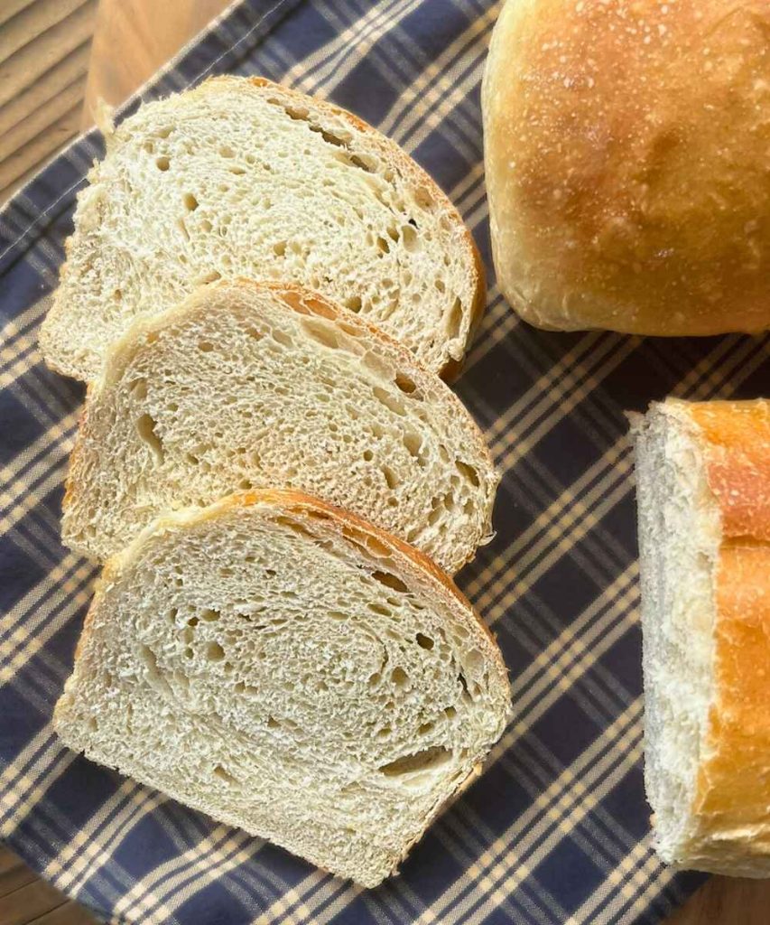 2 loaves of high altitude sourdough sandwich bread with 3 slices cut off one loaf