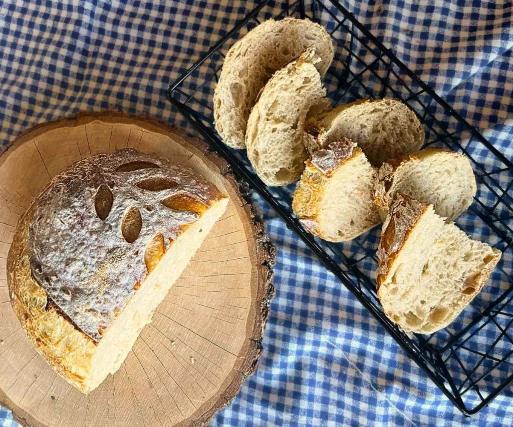 slices of high altitude sourdough bread in a bread basket next to the whole loaf