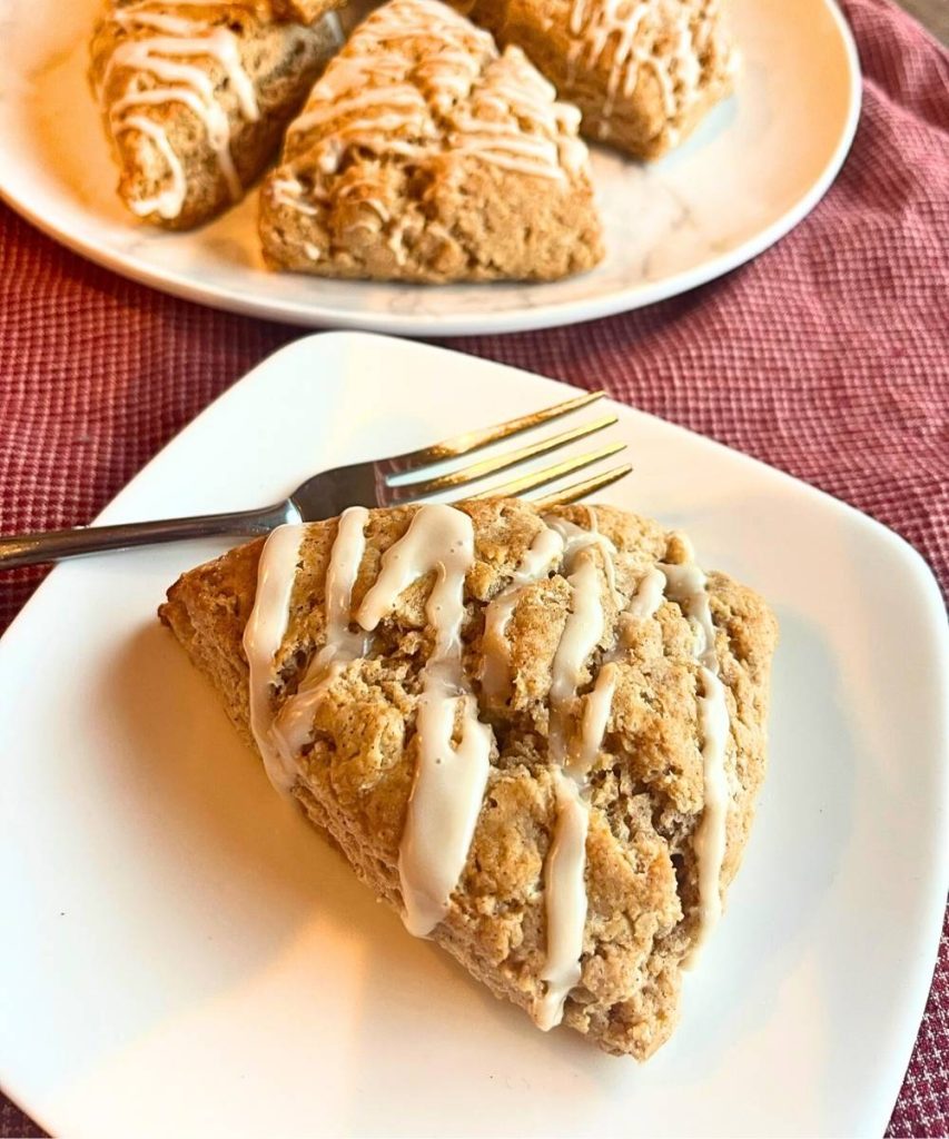 a high altitude cinnamon scone on a white plate with a fork next to it