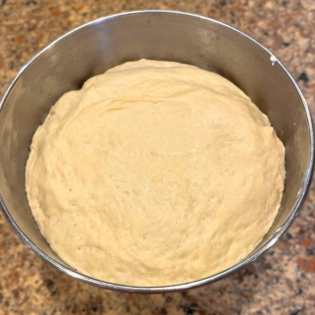 a mixing bowl with fully proofed sourdough English muffin dough