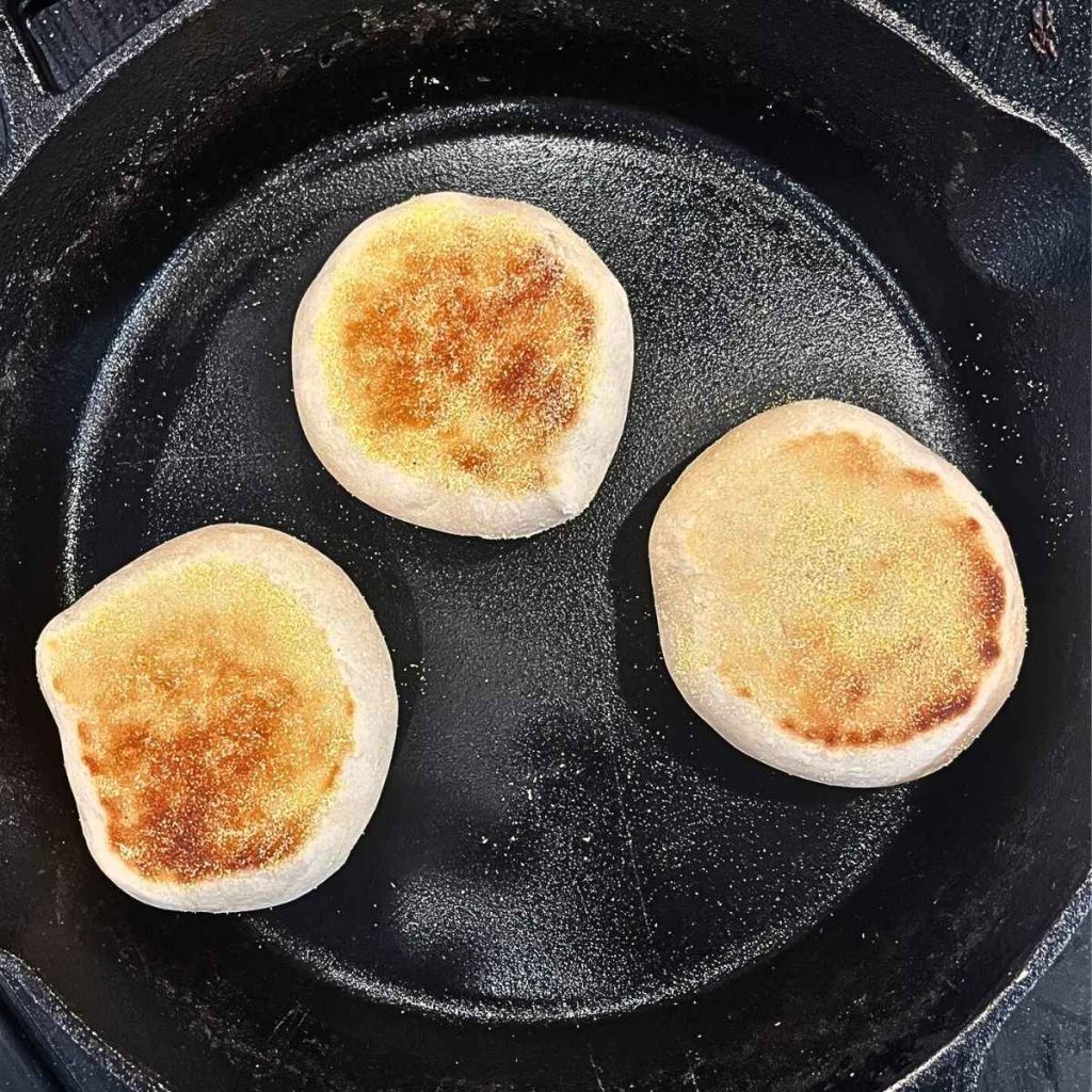sourdough English muffin being cooked in a cast iron skillet