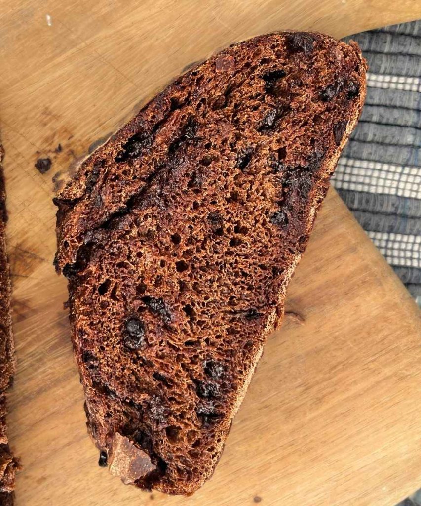 a slice of high altitude sourdough chocolate bread on a cutting board