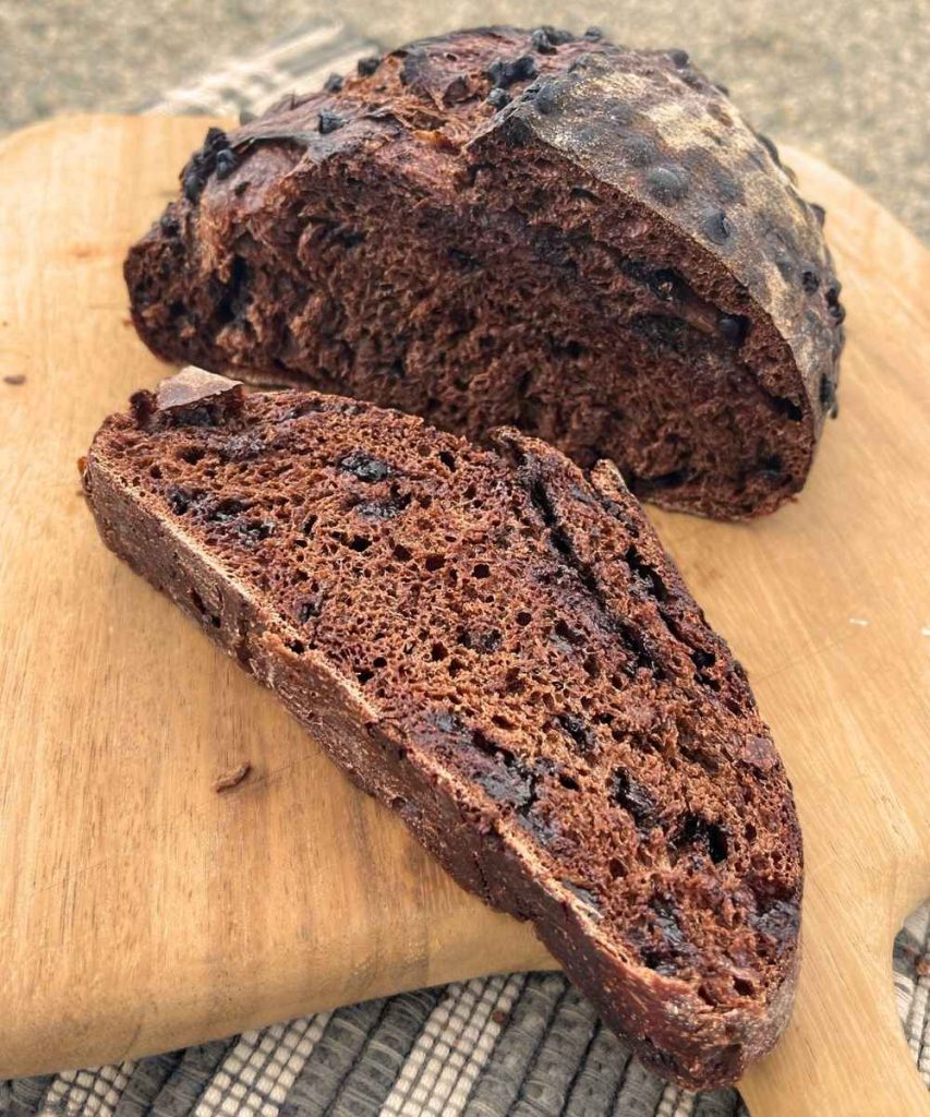 a slice off a sourdough double chocolate bread loaf on a cutting board