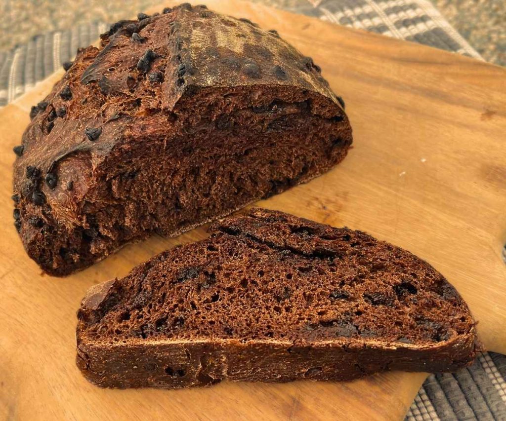 a slice of high altitude sourdough chocolate bread on a cutting board